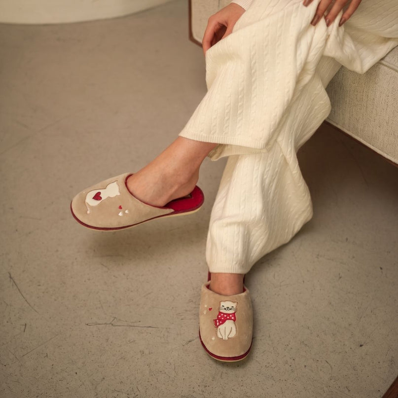 Close-up of BELSTA The Kitty Velour Slippers worn with cream pajamas — beige velour mules with embroidered cats